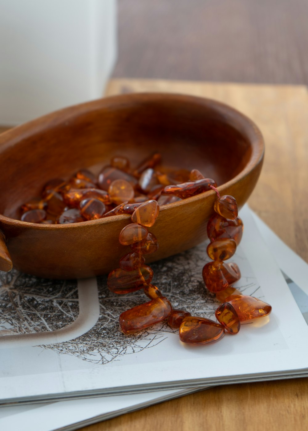 a wooden bowl filled with glass beads on top of a table