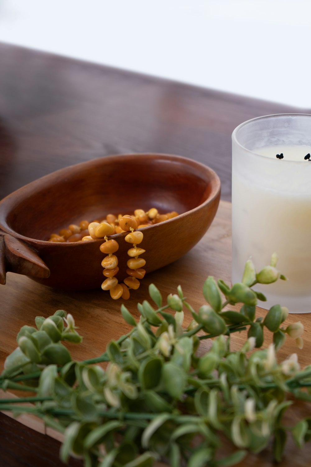 a glass of milk next to a bowl of flowers