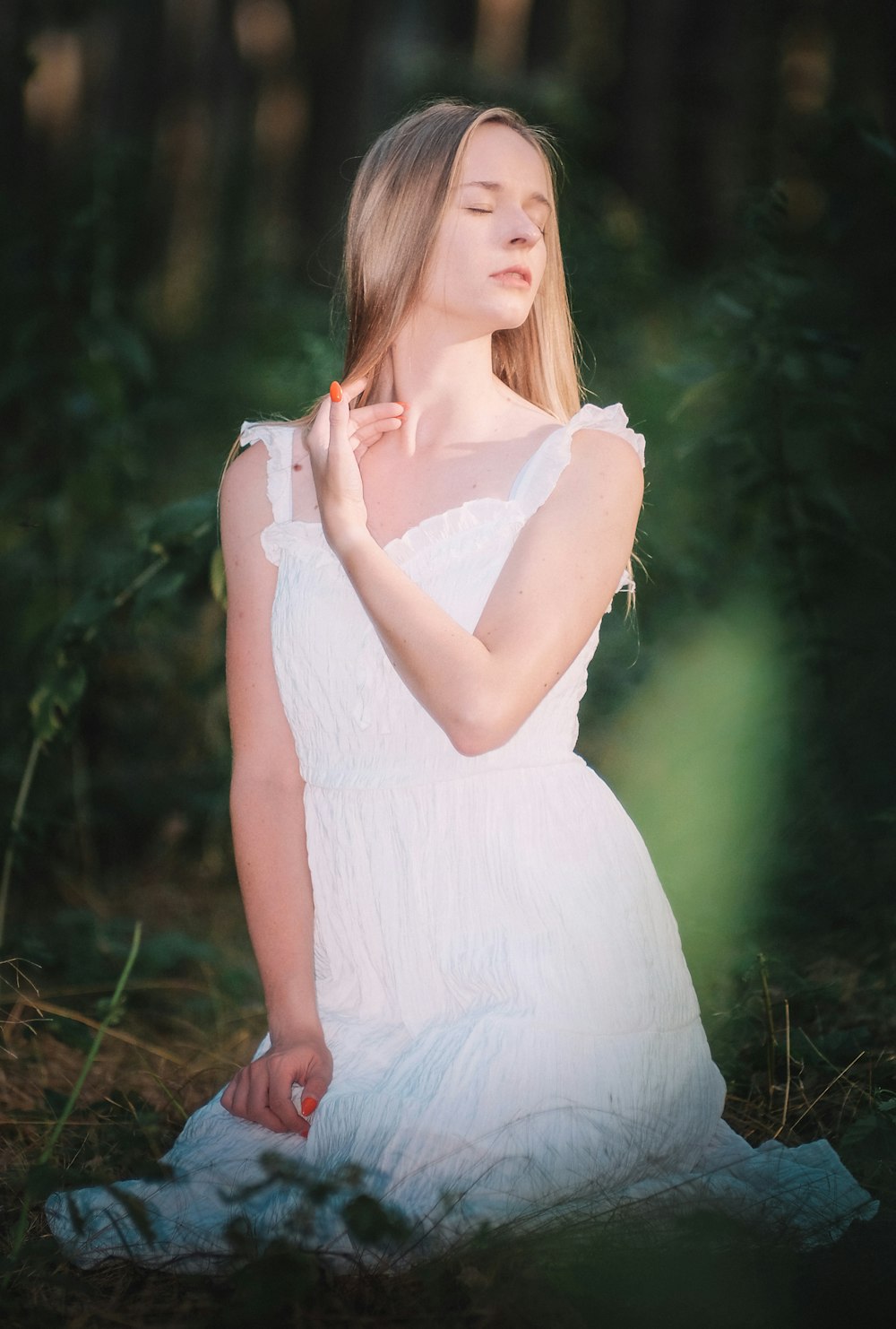 a woman in a white dress sitting in the woods