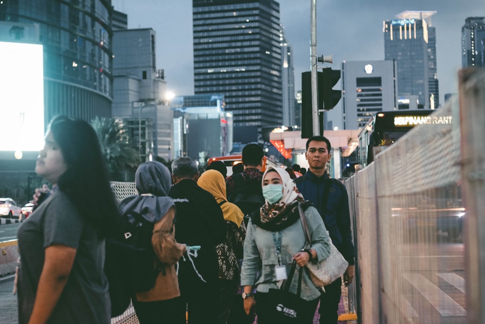 a group of people walking down a street next to tall buildings