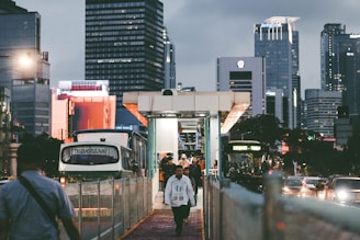 a group of people walking down a sidewalk next to tall buildings