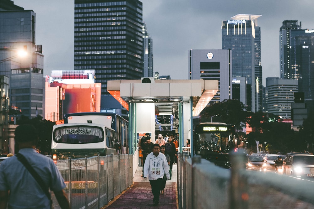 a group of people walking down a sidewalk next to tall buildings