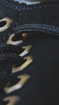Close-up of black fabric with metallic eyelets threaded with a black cord, showcasing detailed stitching and texture.