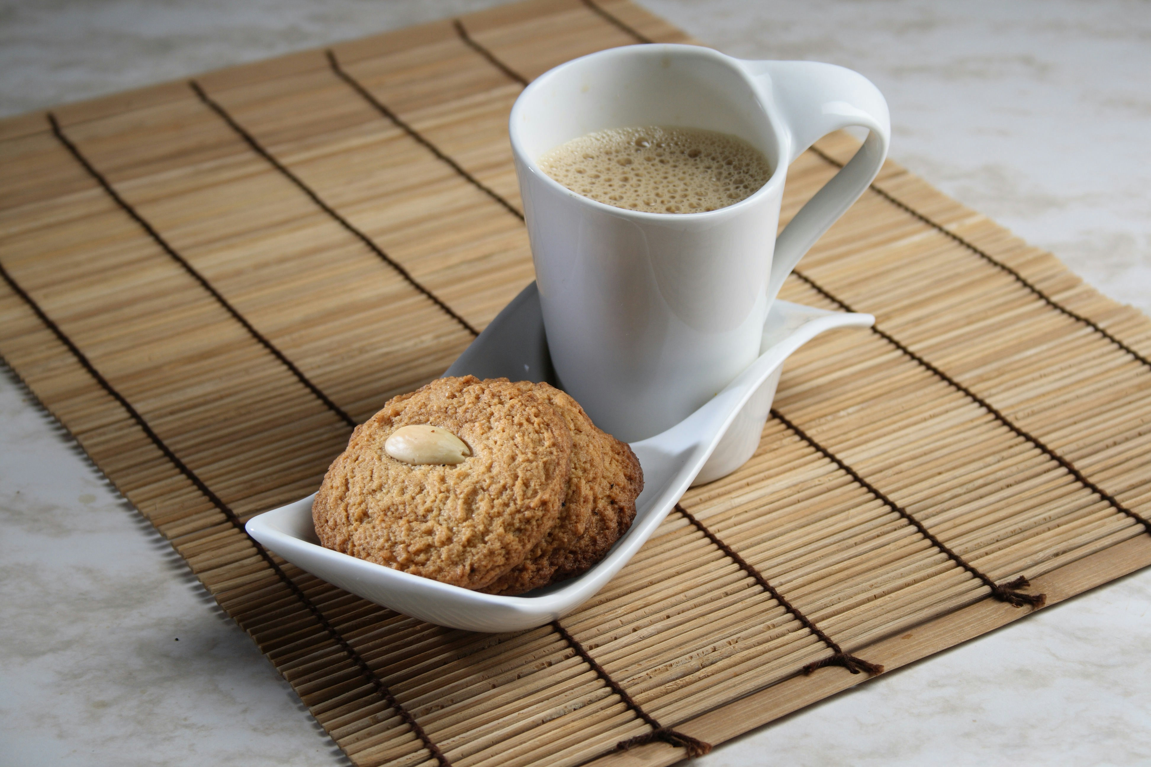 a cup of coffee and a cookie on a mat