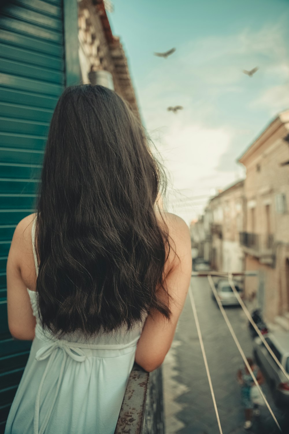 a woman standing on a balcony looking out at the street