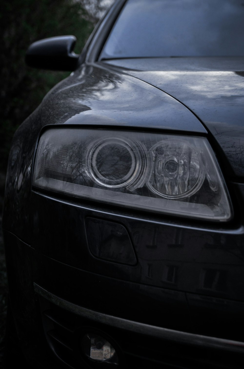a close up of a car's headlight with trees in the background
