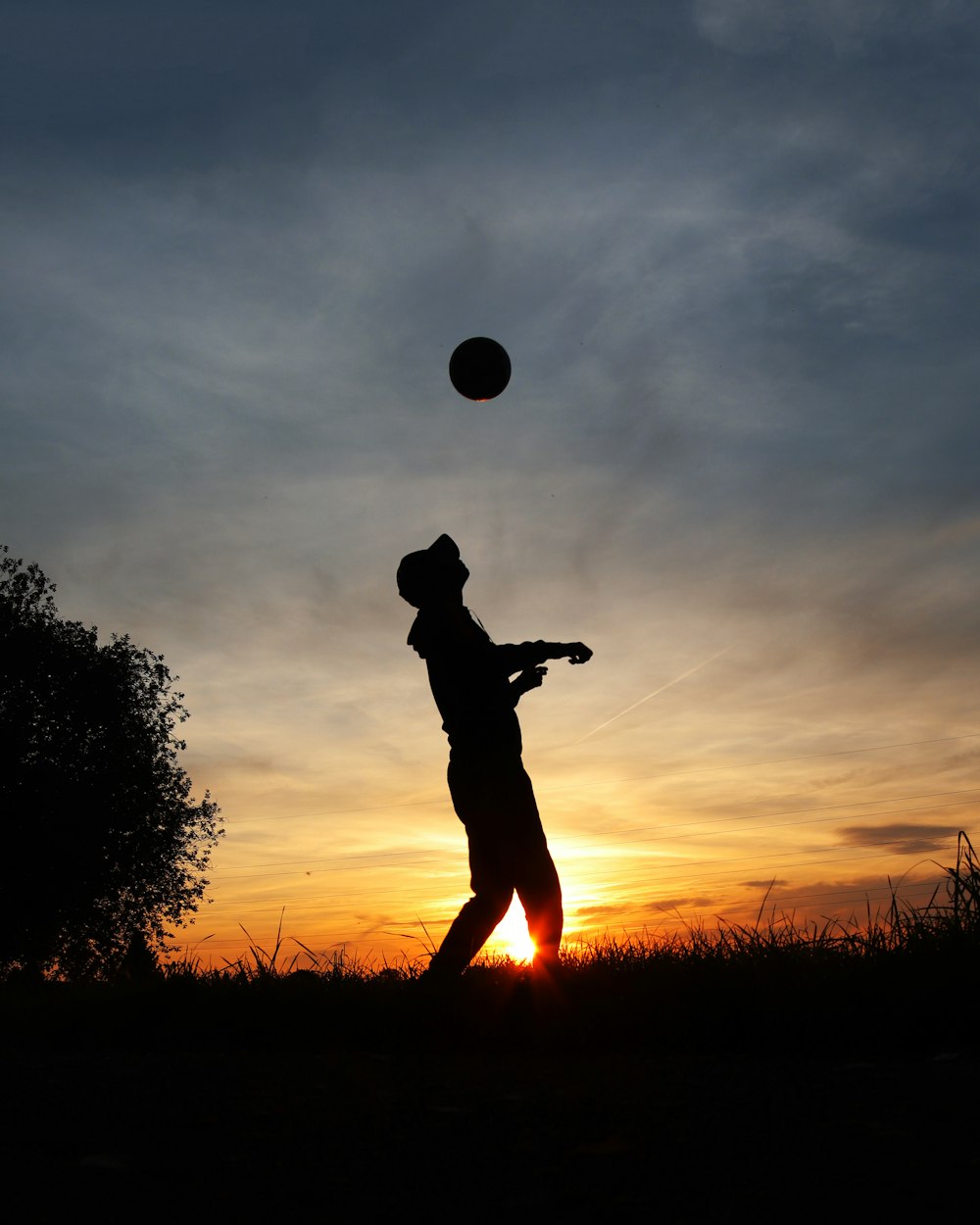 a silhouette of a person playing with a ball