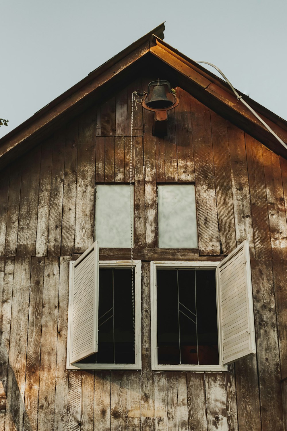 a wooden building with two windows and a bell