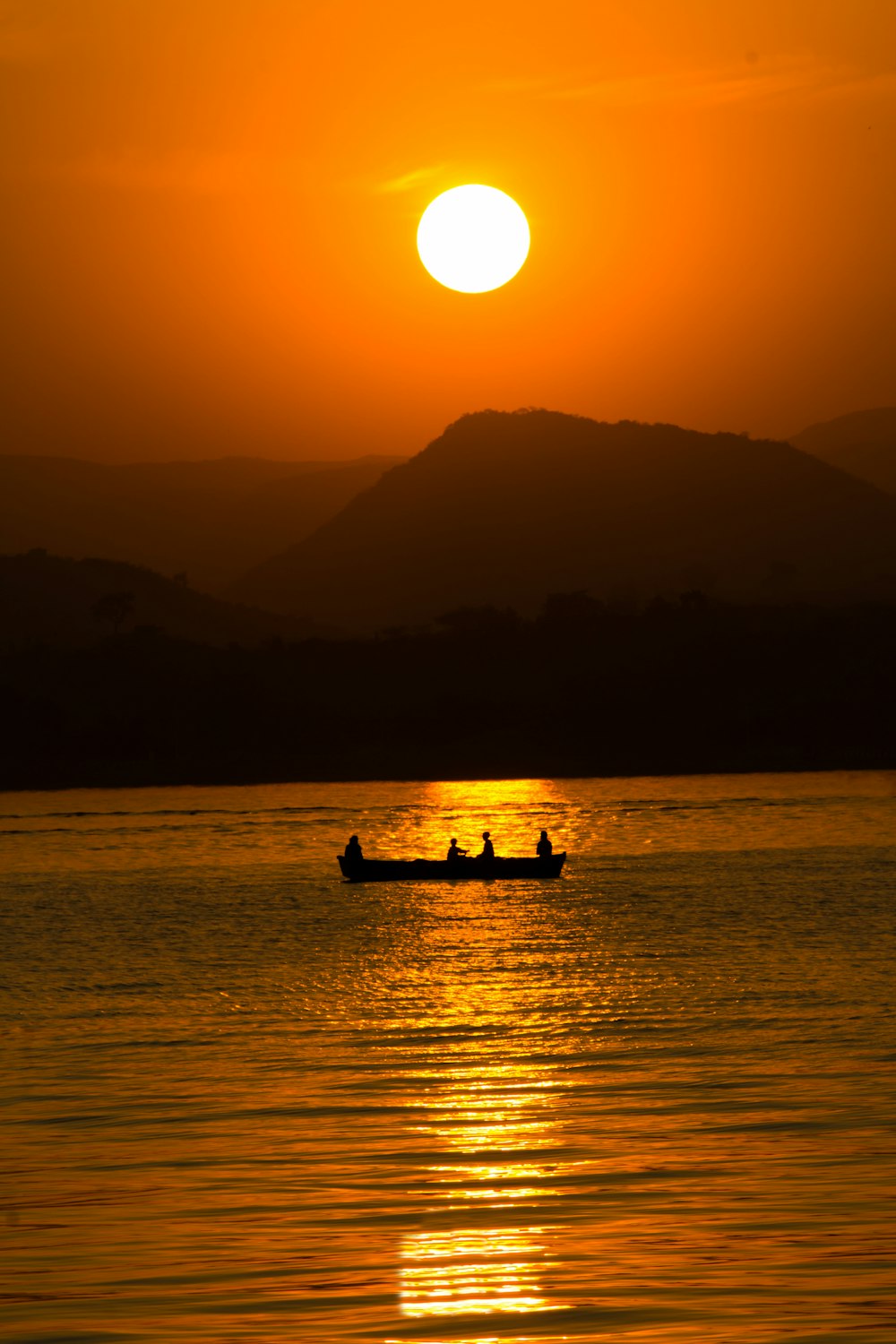 the sun is setting over the water with a boat in the foreground
