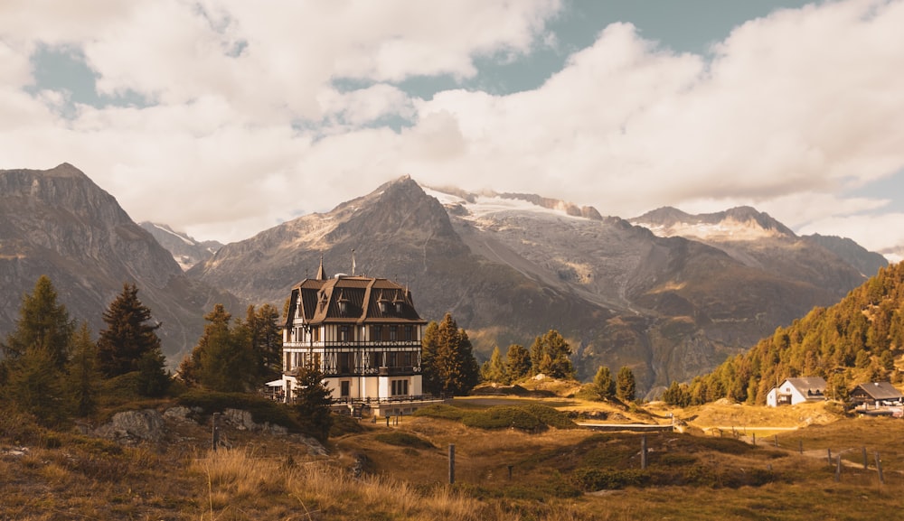 a house in the middle of a field with mountains in the background