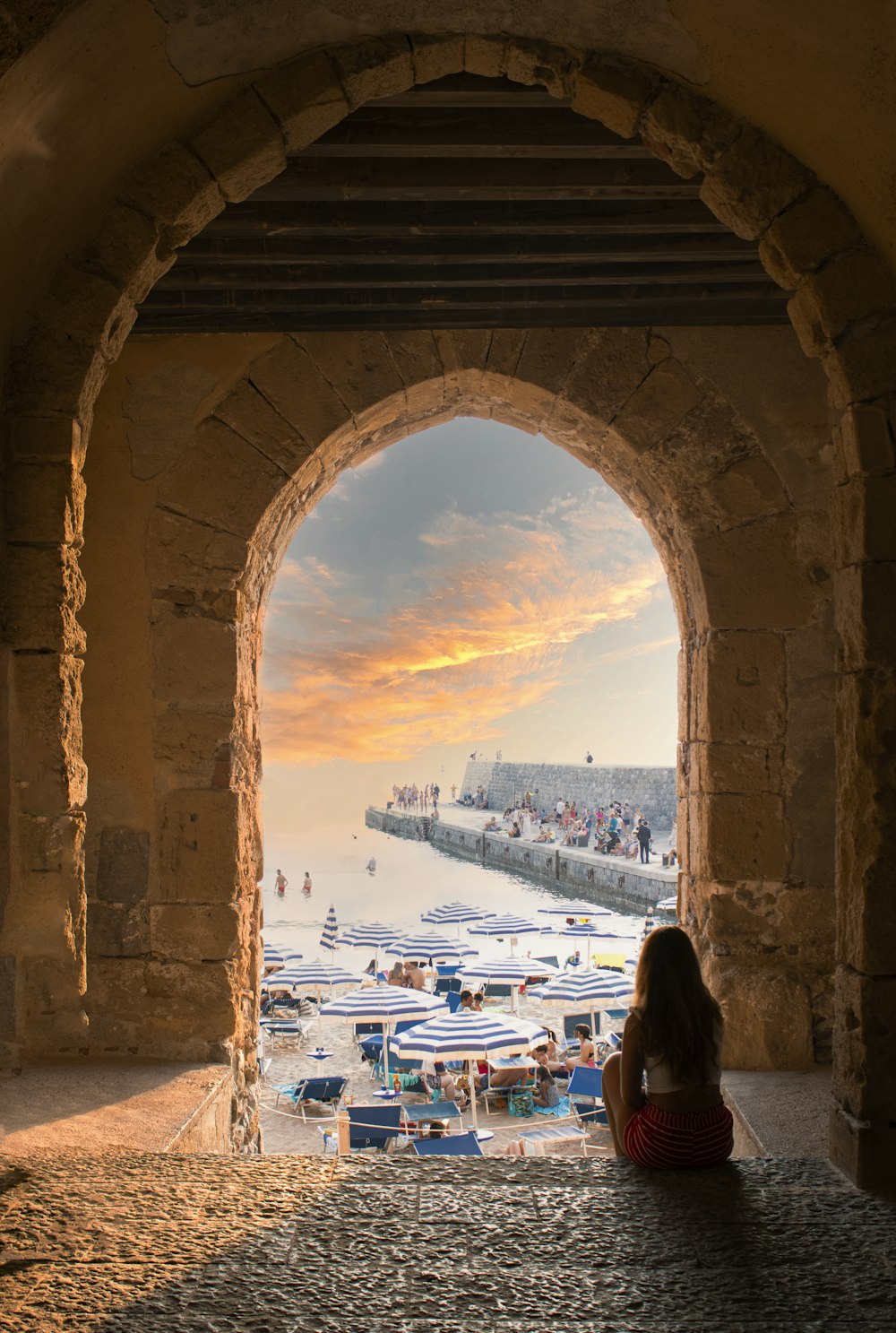 a woman sitting on the ground looking out at the water