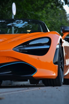 an orange sports car parked on the side of the road
