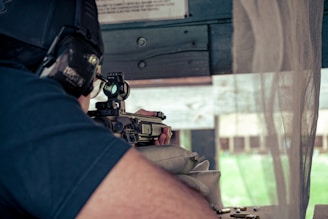 a man holding a gun and aiming it at a target at a gun range