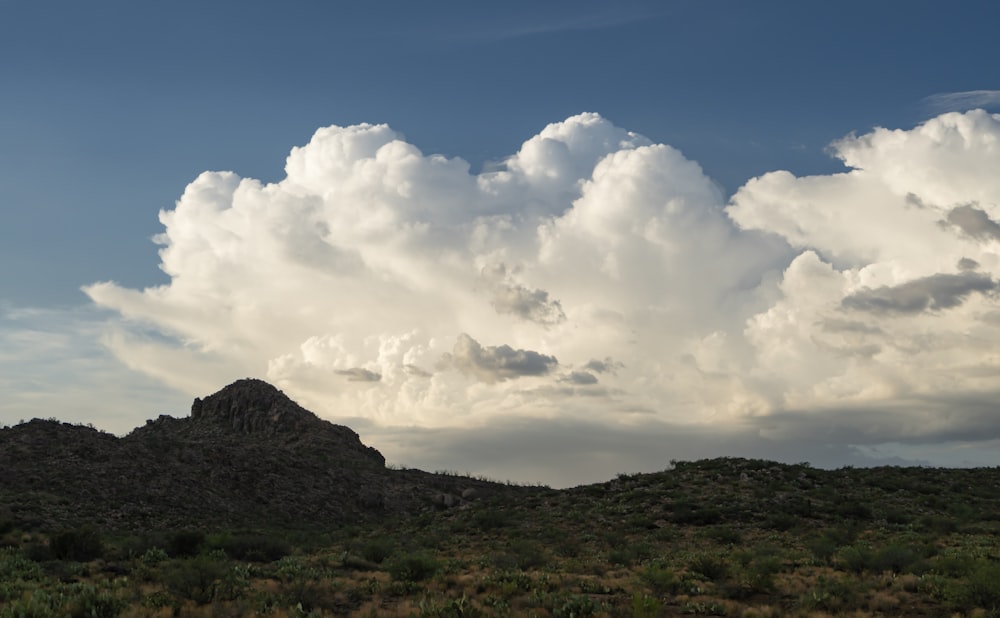 a large cloud is in the sky over a mountain