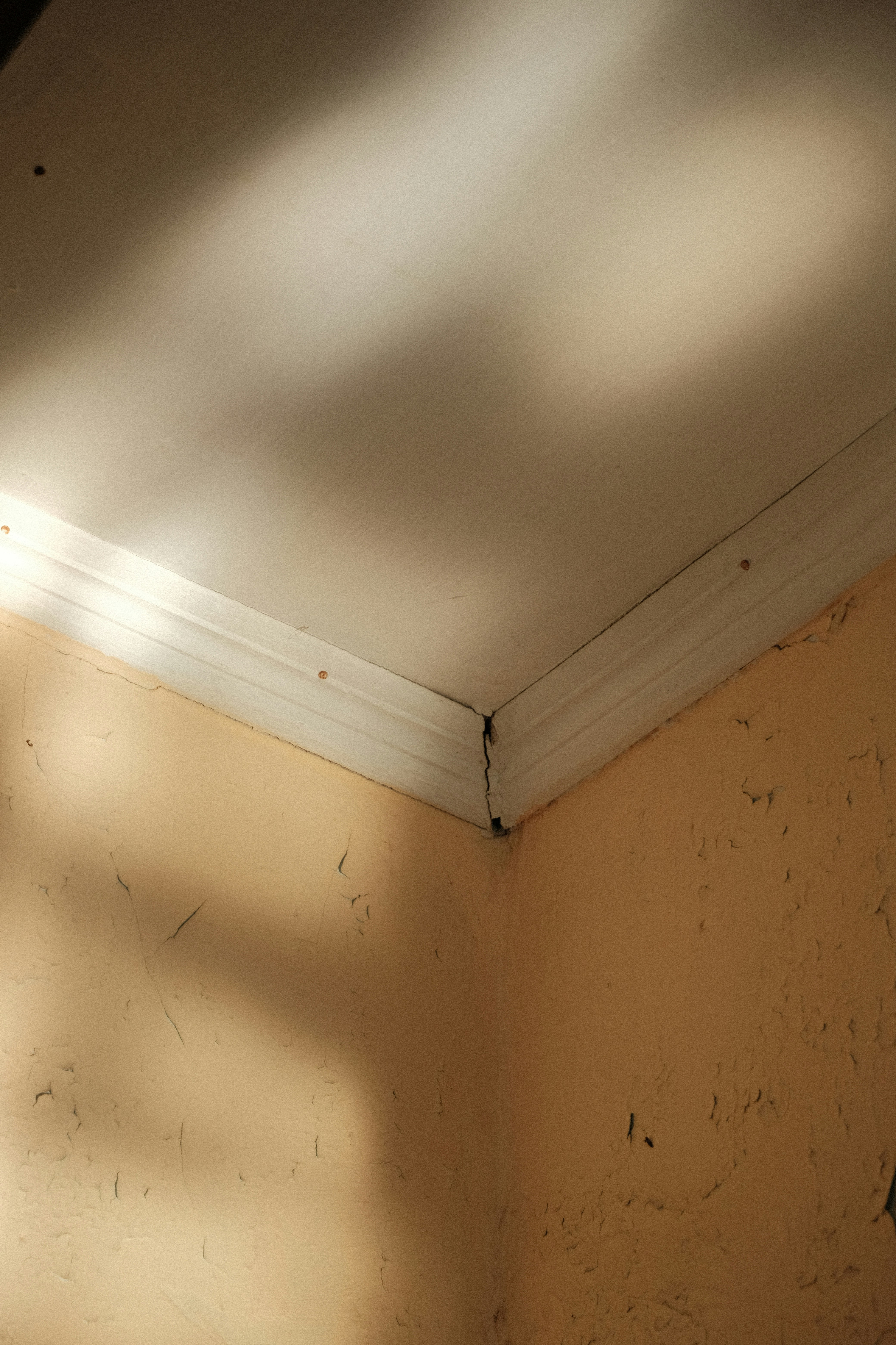 a corner of a room with a light coming through the ceiling