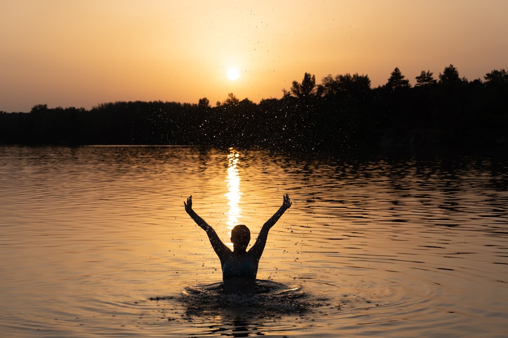 a person in a body of water with their arms in the air