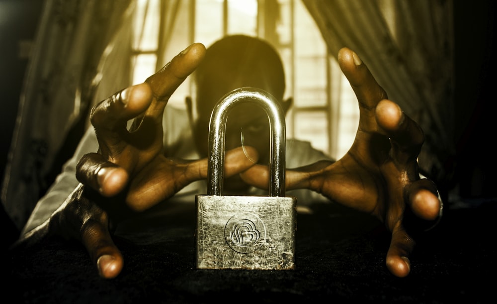 a person holding a padlock in front of a window