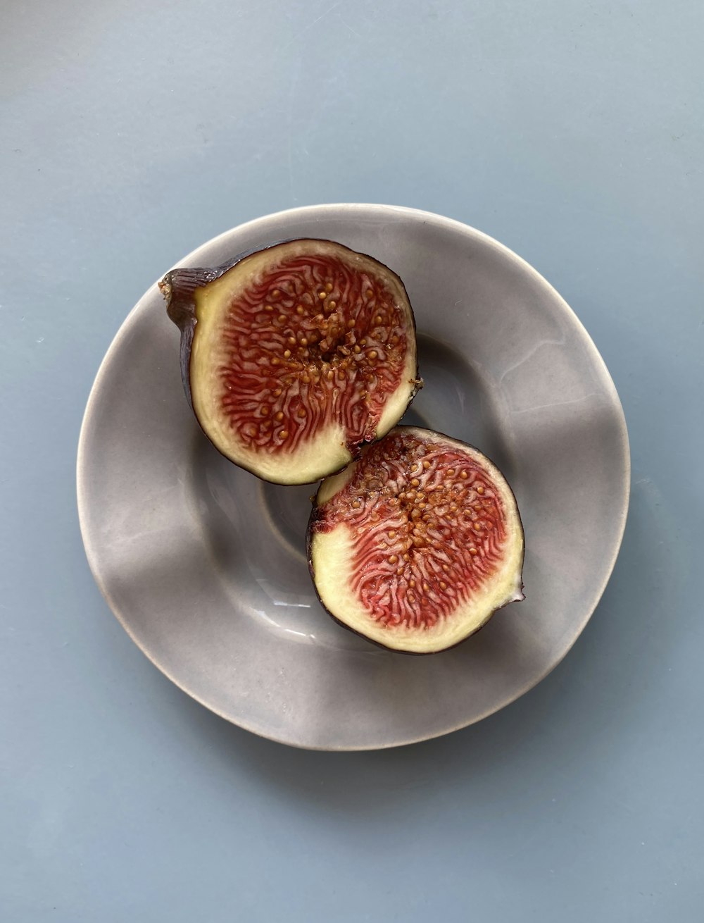 two figs on a plate on a blue table