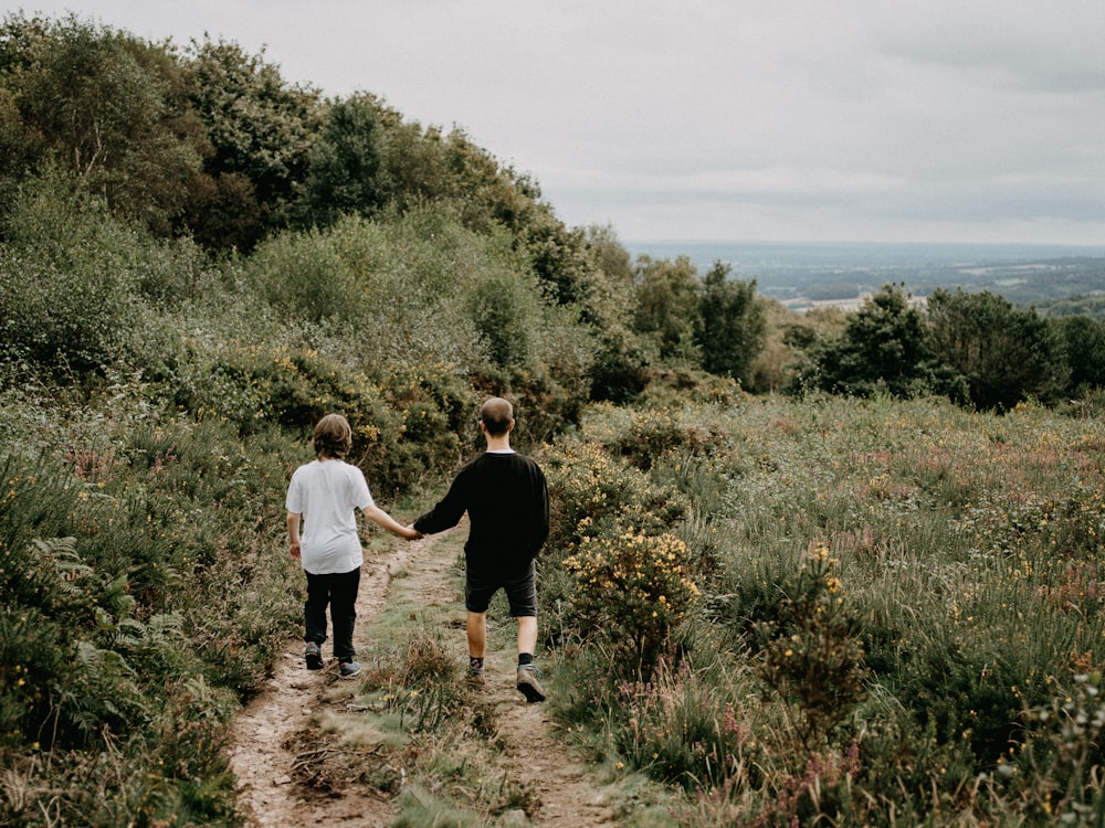 a couple of people walking down a dirt road