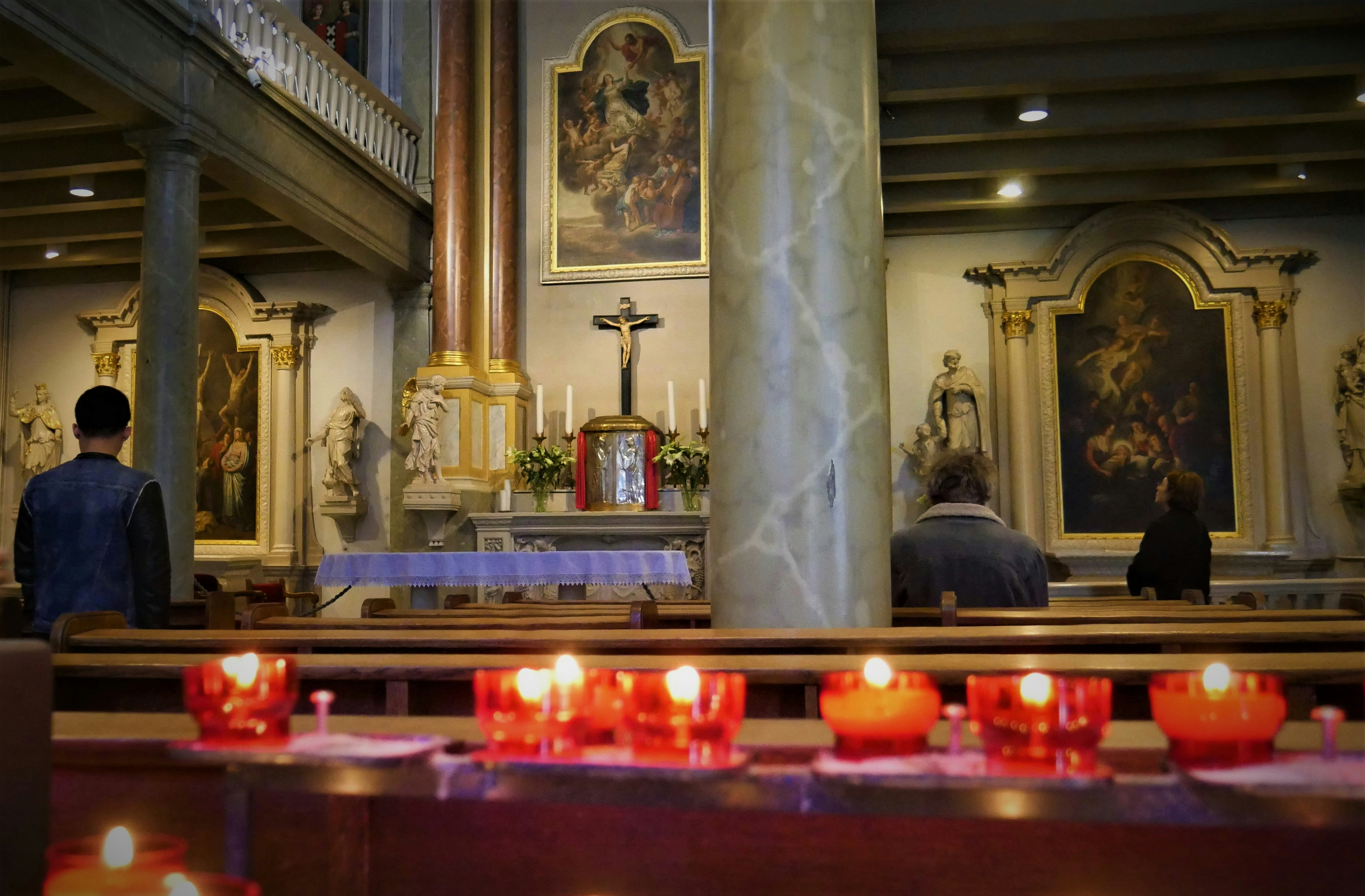 a couple of people standing in a church with candles, 15th Century Church inside of  the famous women community: Begijnhof