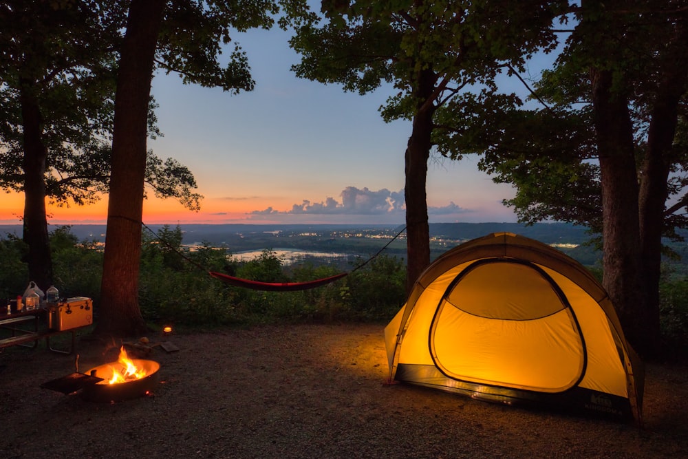 a tent set up in the woods at sunset