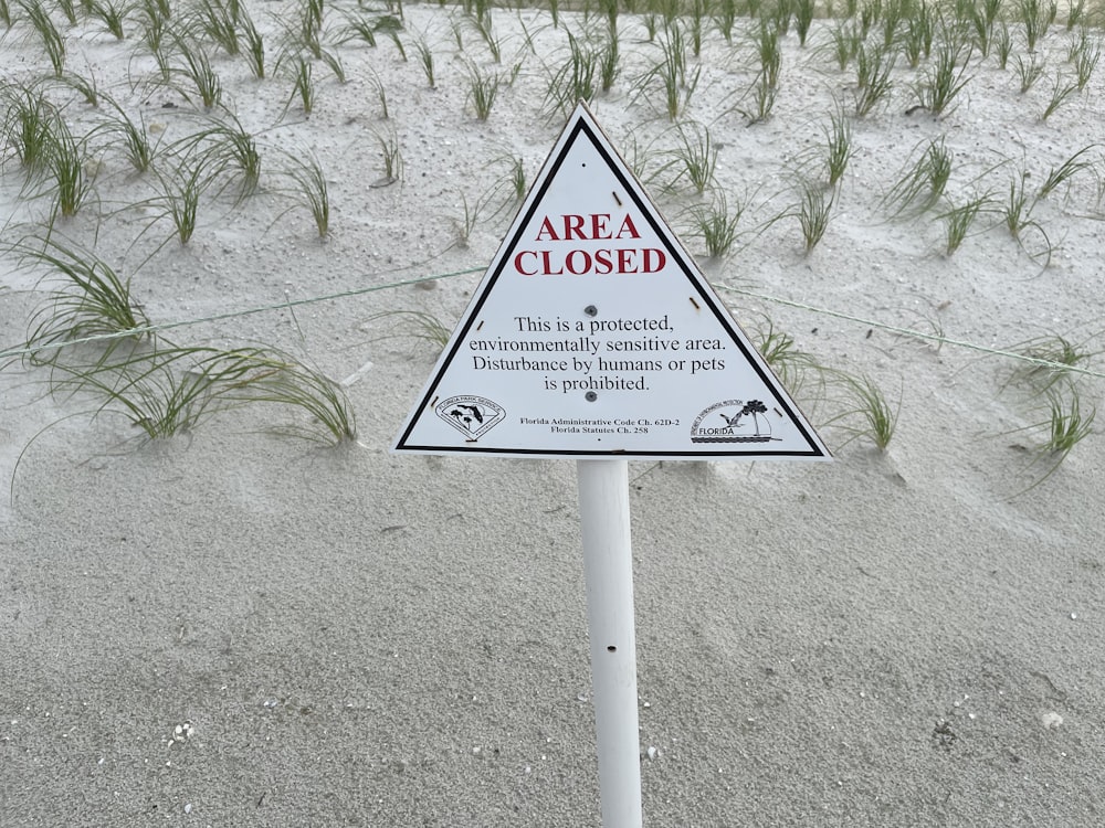 a warning sign on a beach with grass in the background
