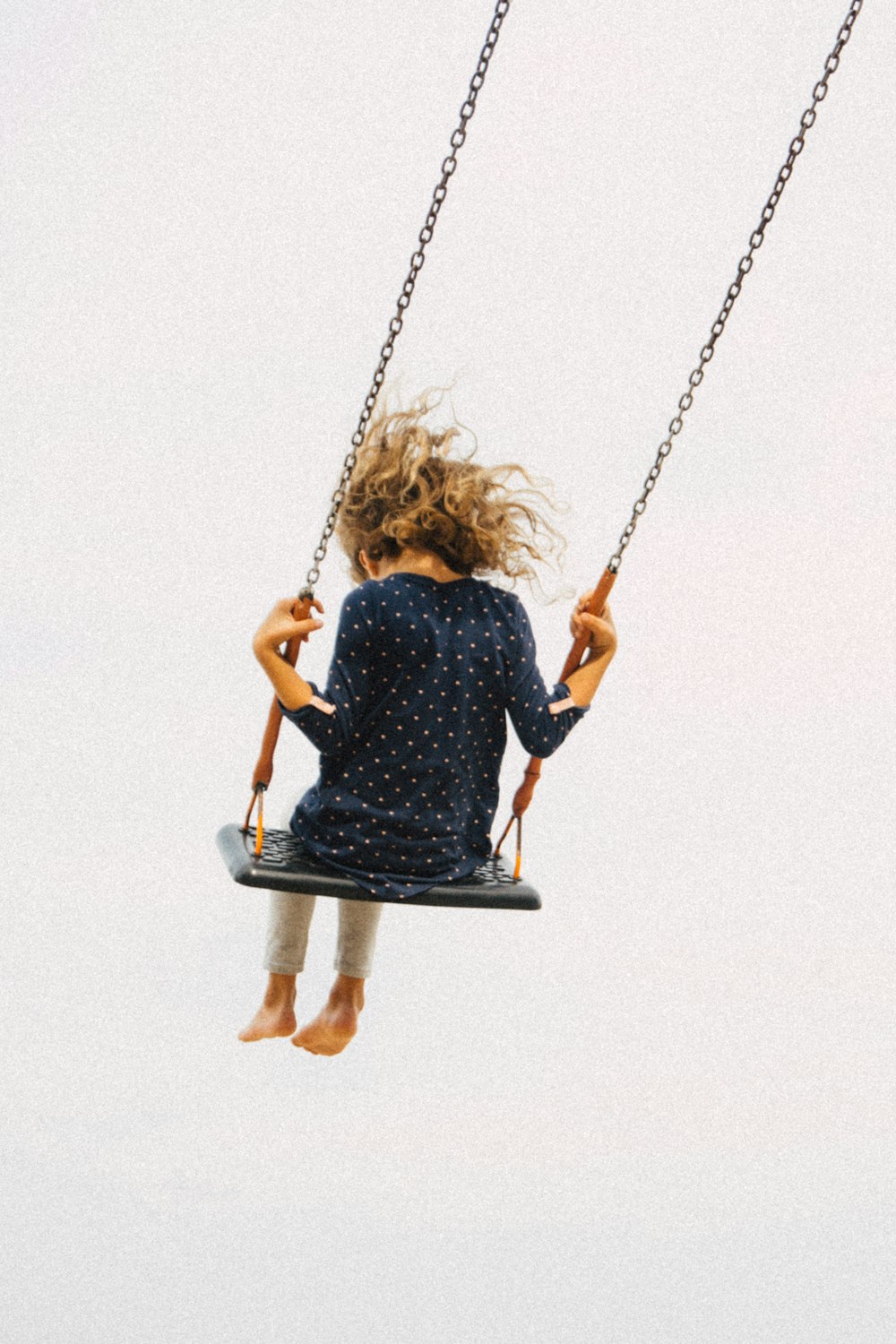 a little girl is swinging on a swing