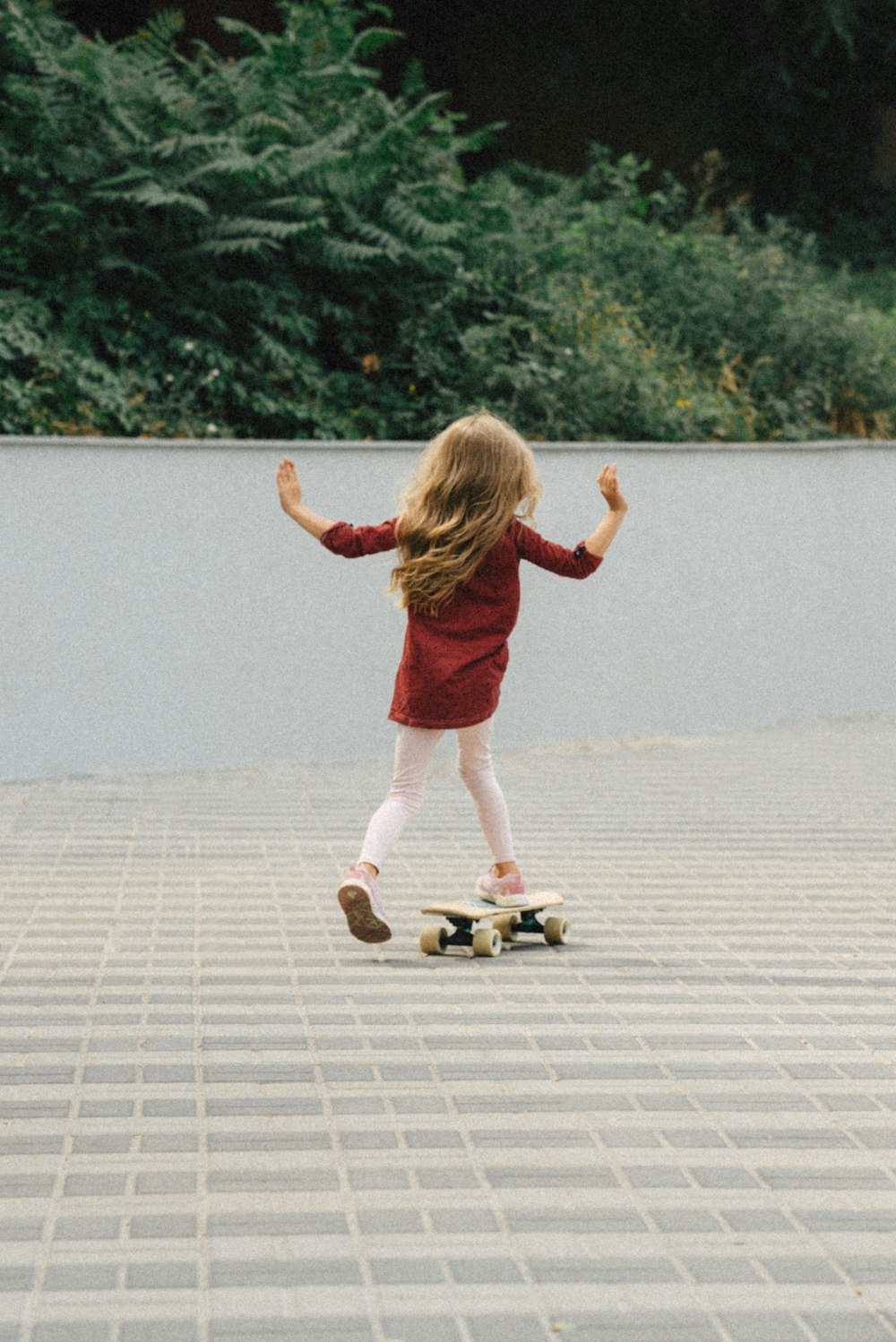 a little girl riding a skateboard down a sidewalk