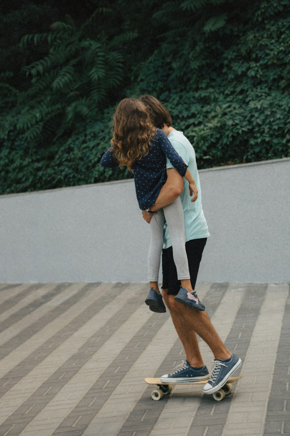 Ein Mann auf einem Skateboard mit einem kleinen Mädchen auf dem Rücken