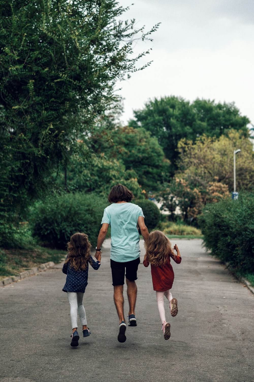 a man and two little girls walking down a road