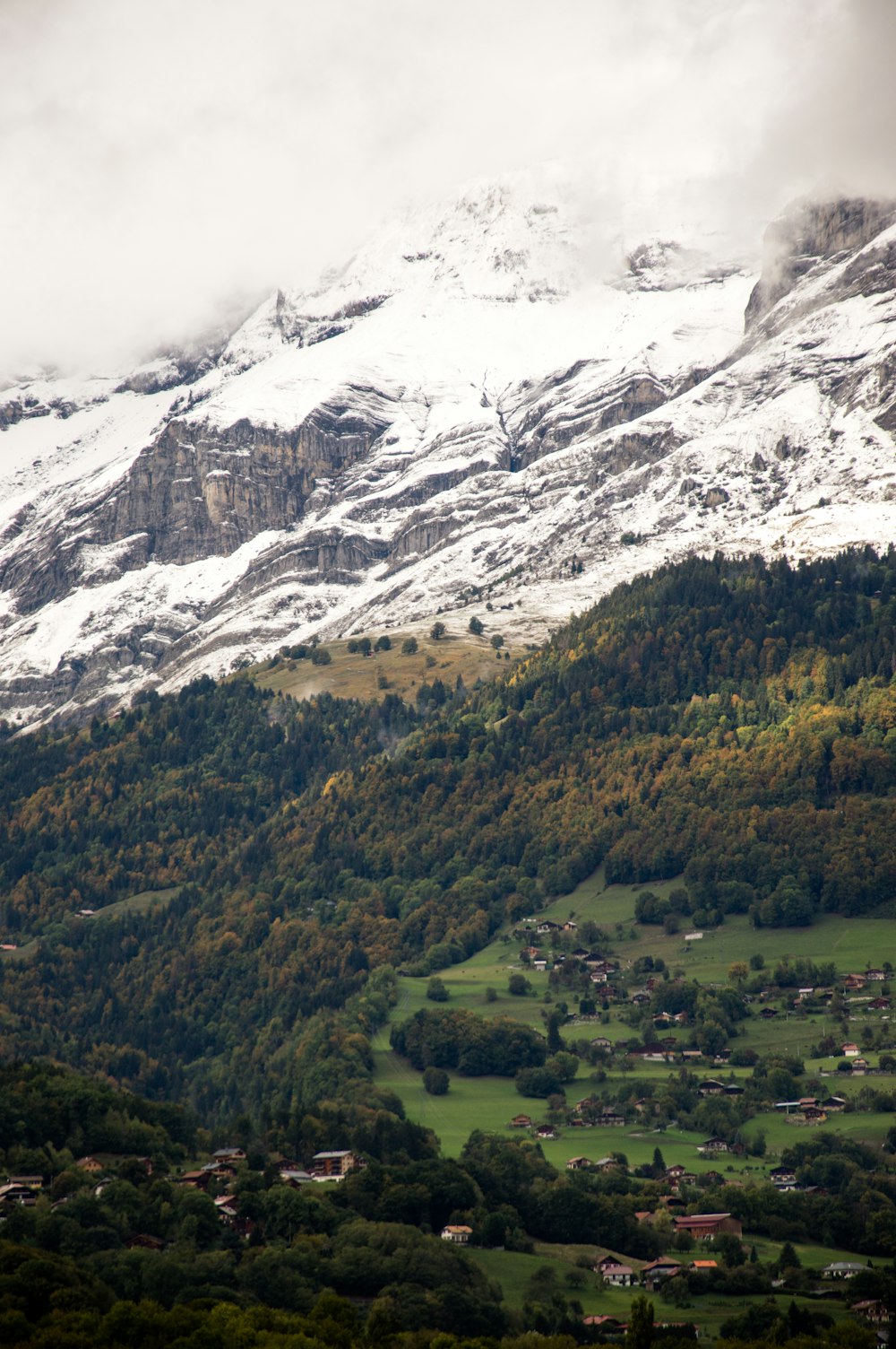 a snowy mountain with a village below it