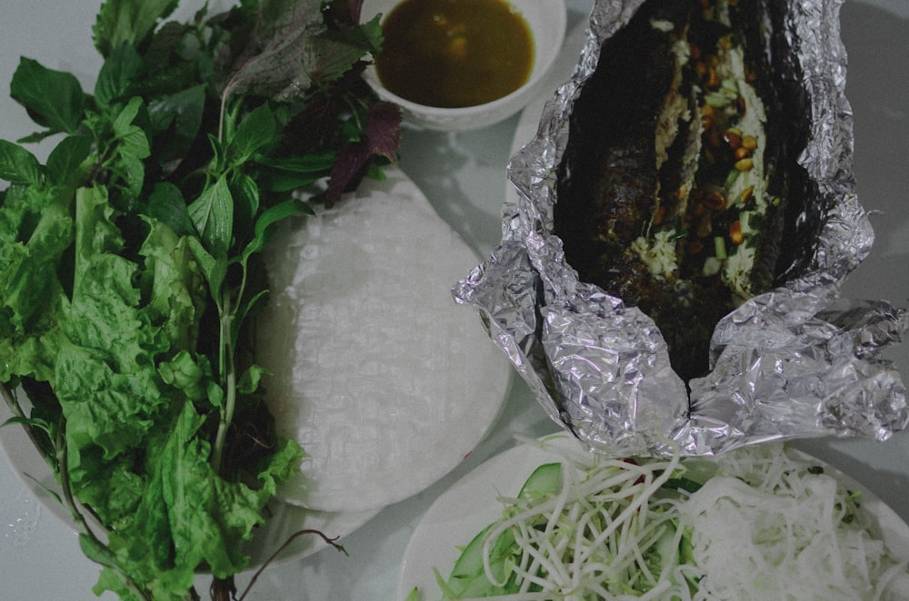 a table topped with plates of food covered in foil