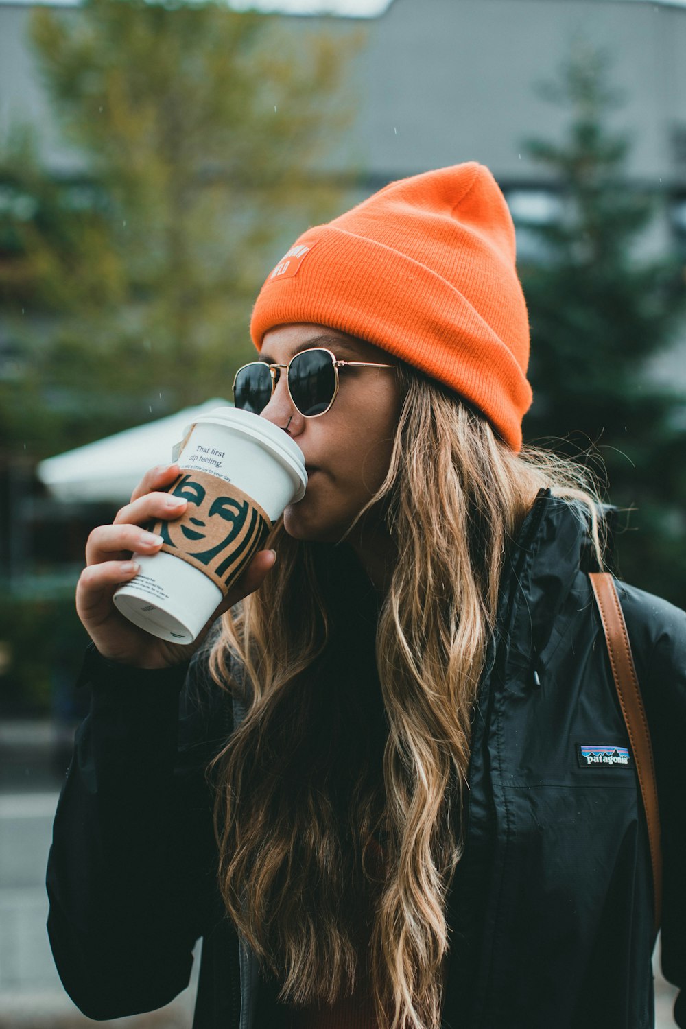 a woman in an orange hat drinking from a coffee cup