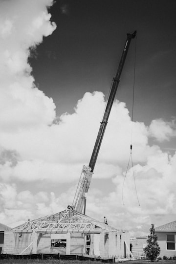 a black and white photo of a crane lifting a house