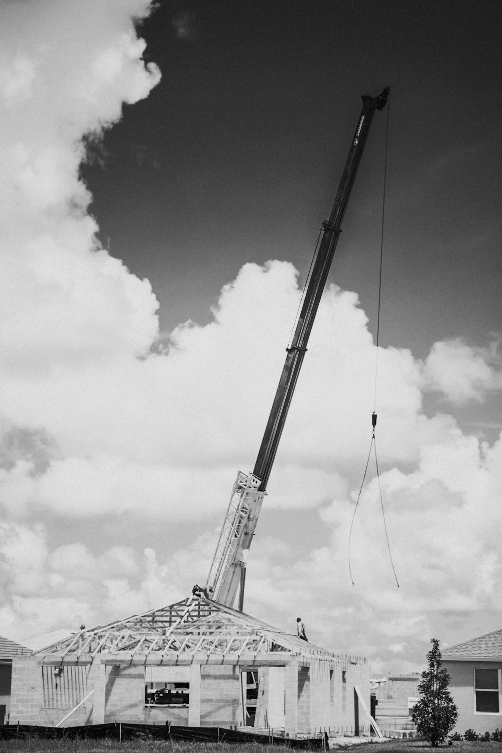 a black and white photo of a crane lifting a house