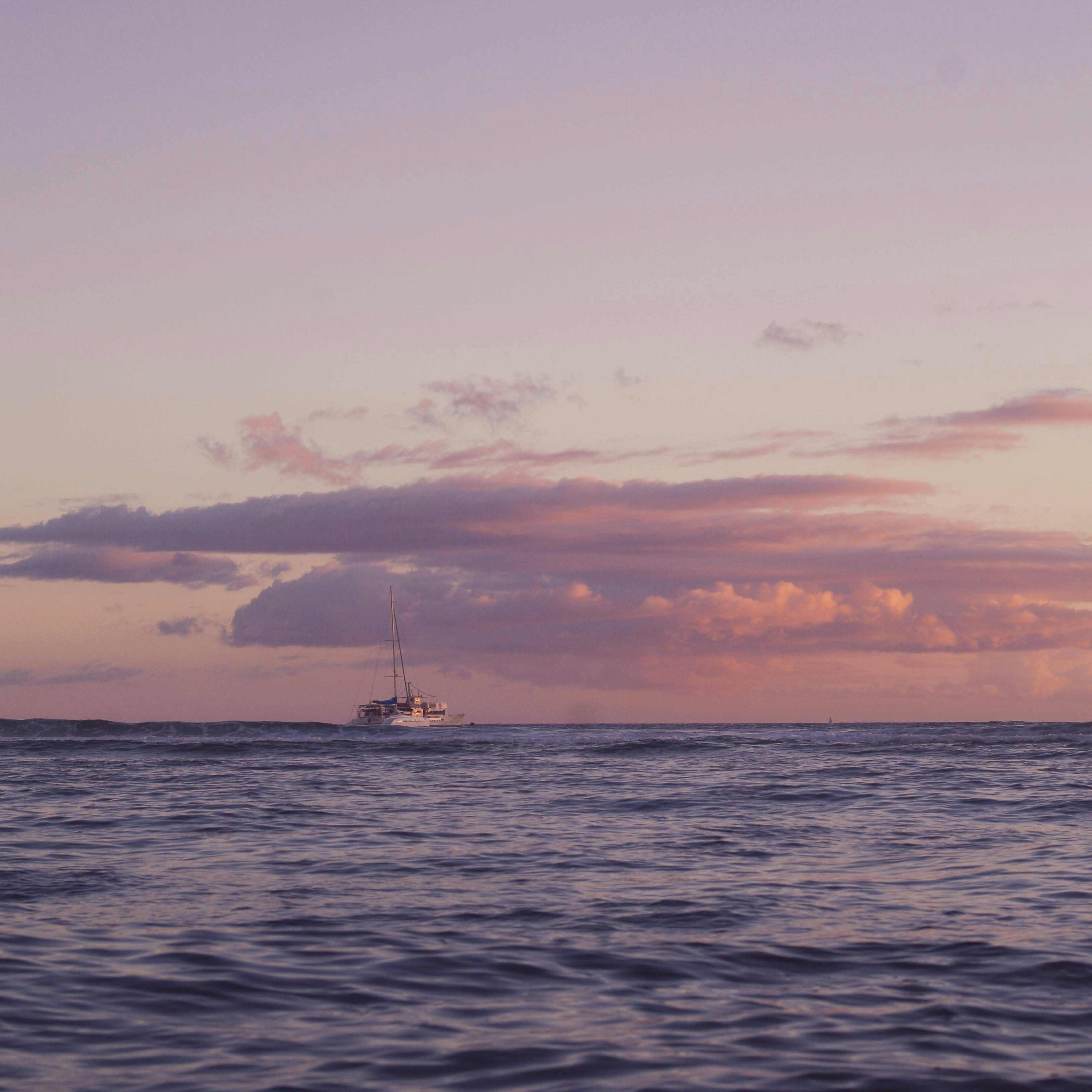 a boat is out in the ocean at sunset