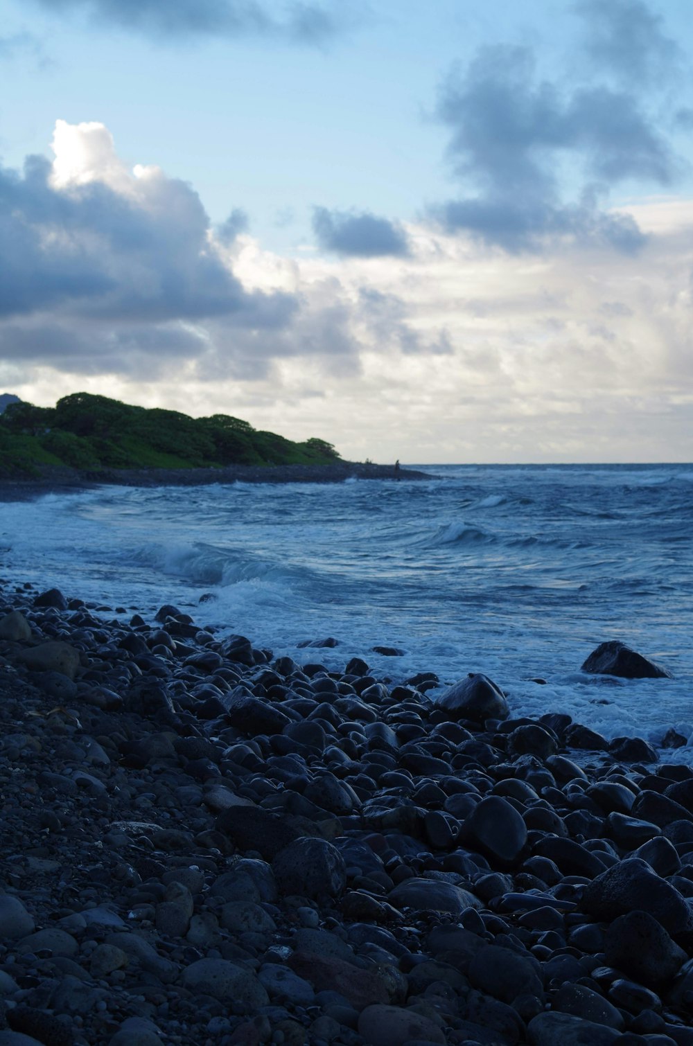 a rocky beach next to the ocean under a cloudy sky