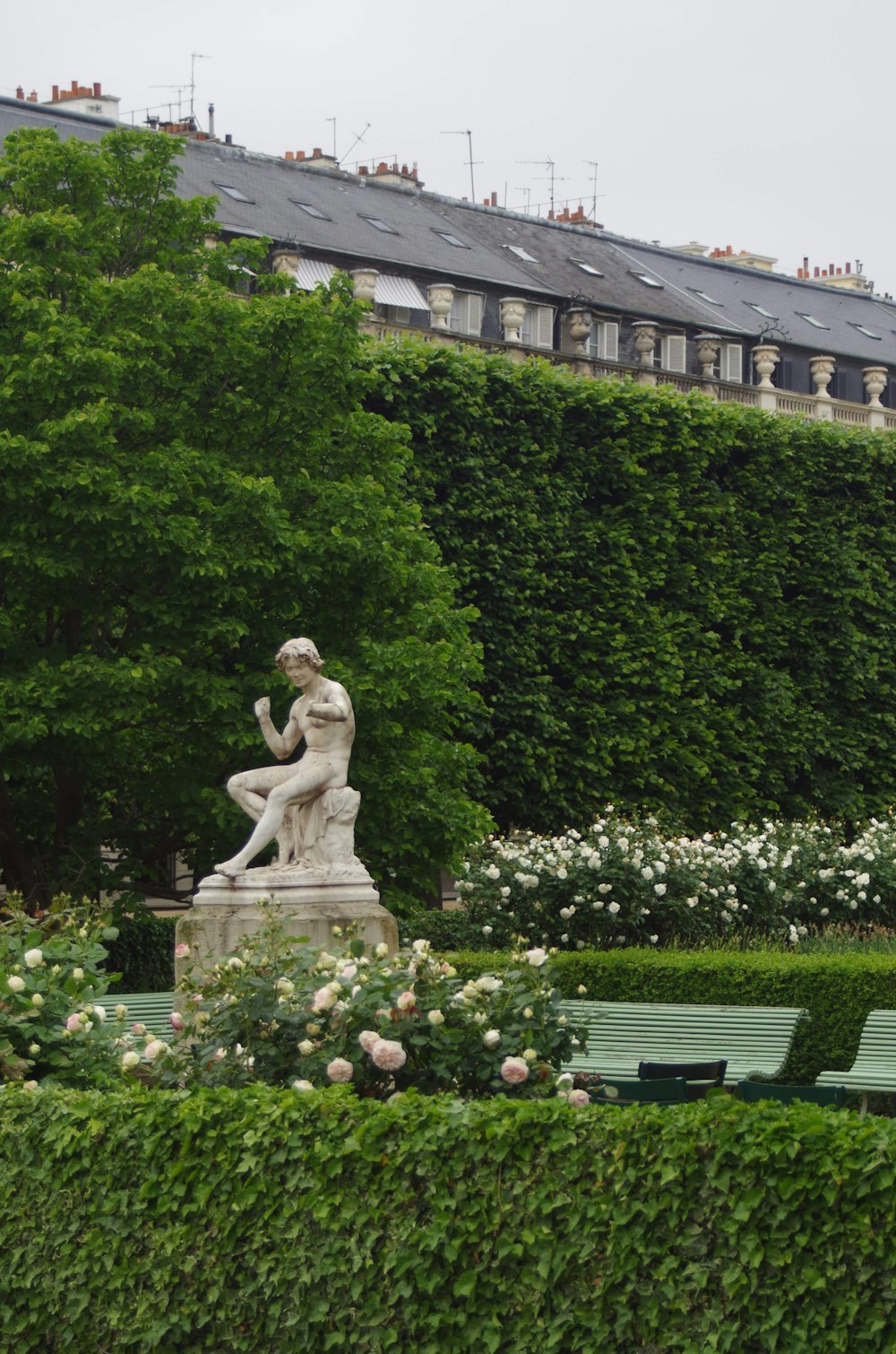 a statue of a woman sitting on a bench in a garden