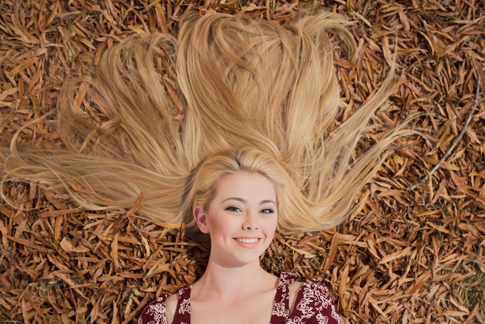 a woman laying on top of a pile of dry grass