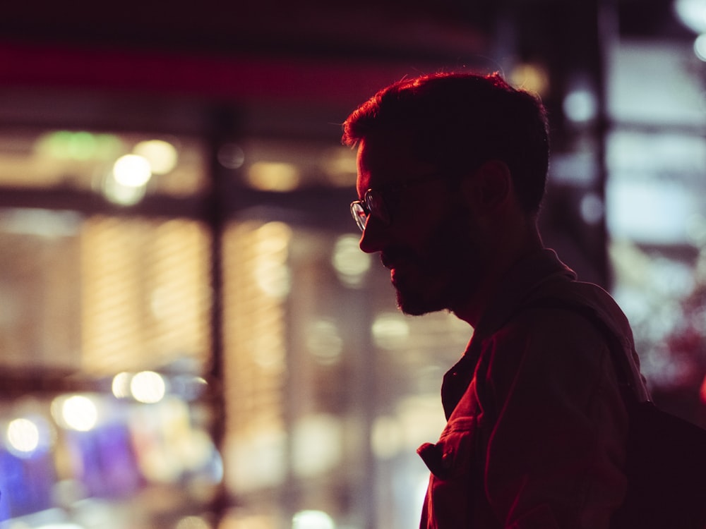 a man with glasses and a backpack standing in front of a building