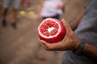 a close up of a person holding a pomegranate