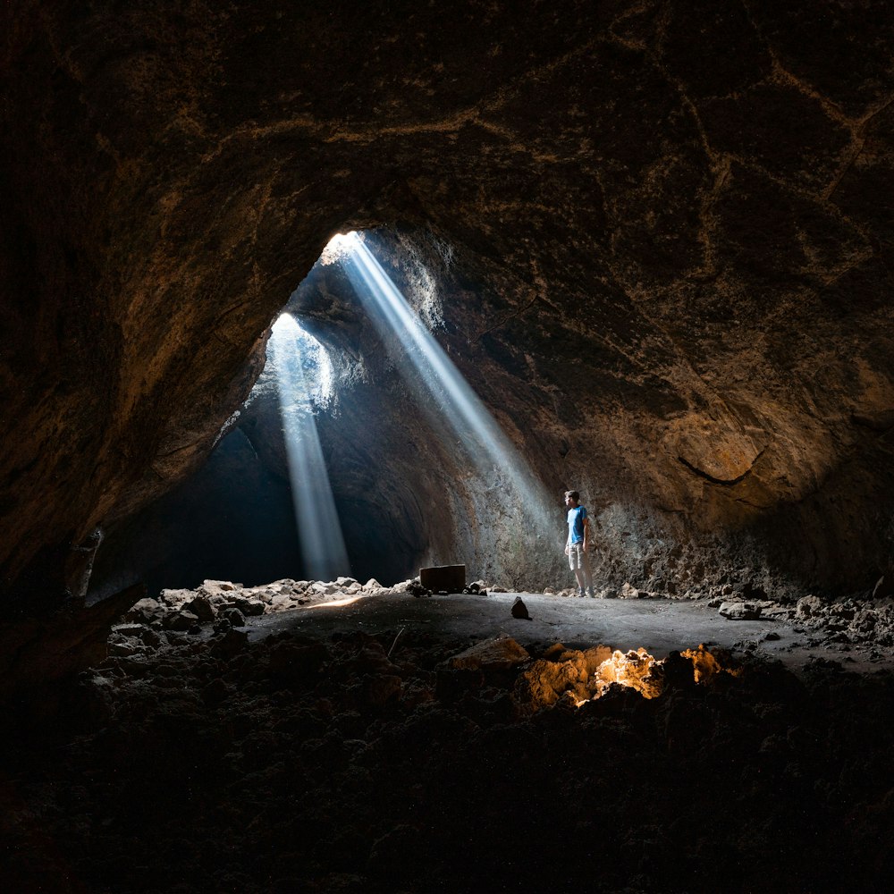 une personne debout dans une grotte avec une lampe de poche