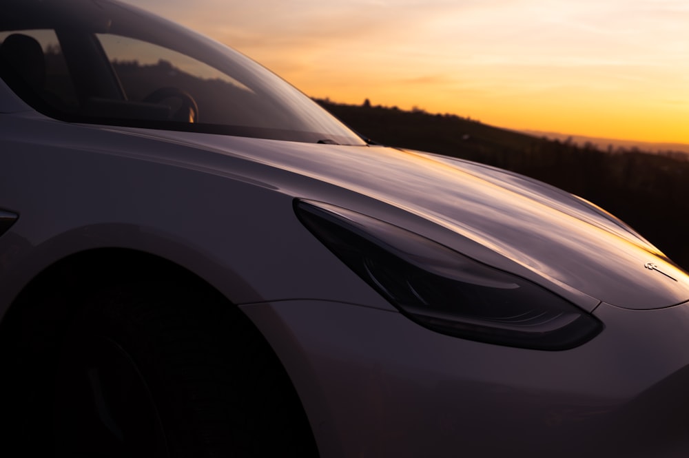 Un primo piano di un'auto con un tramonto sullo sfondo