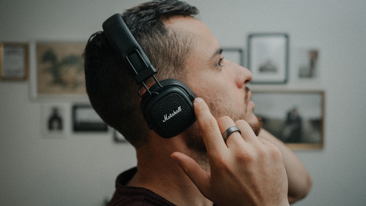 Person listening to music on an iPhone with wireless headphones — the everyday context where an AI DJ shines