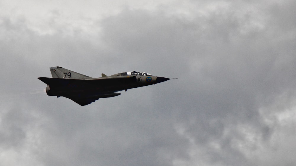 a fighter jet flying through a cloudy sky