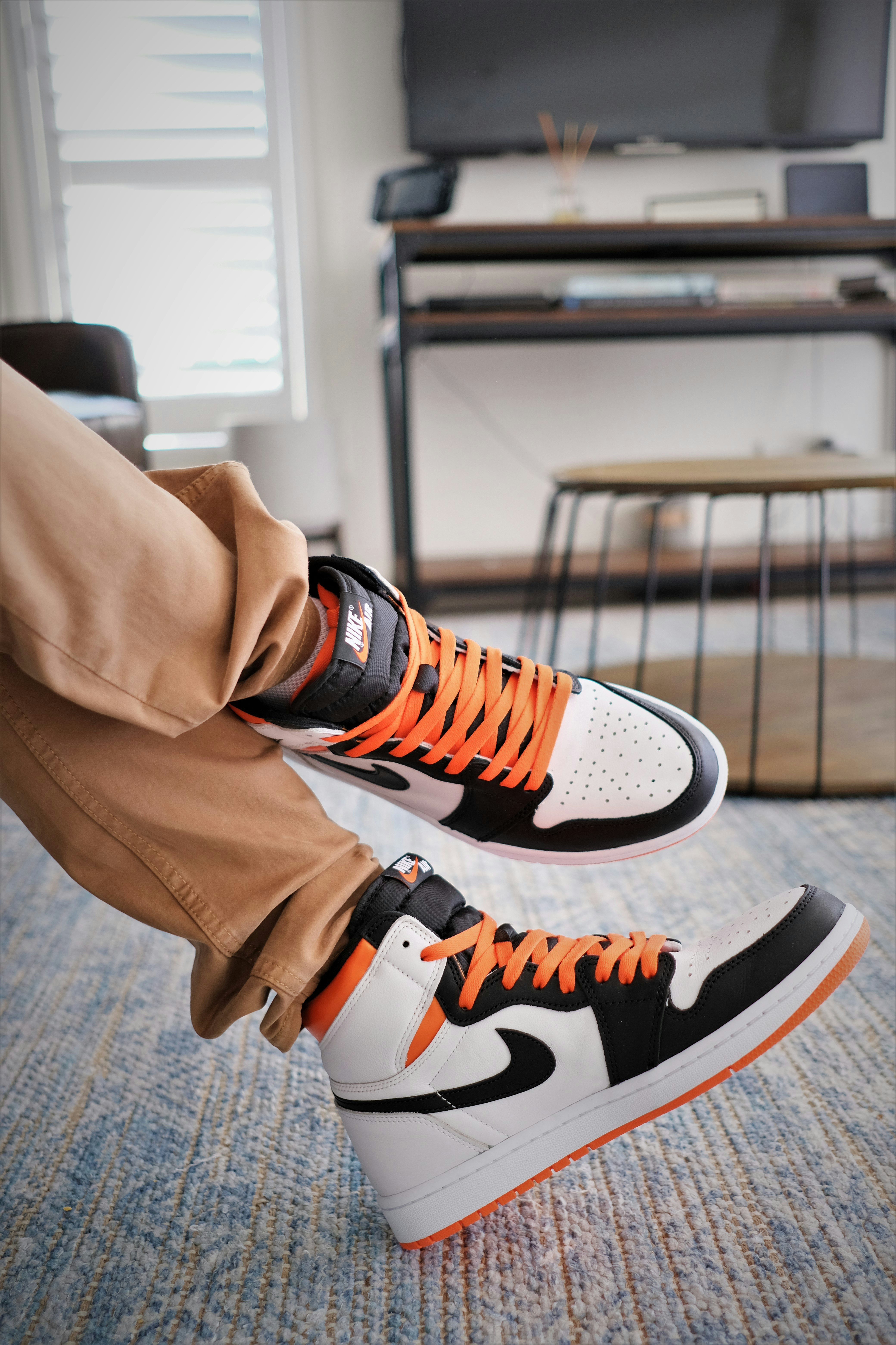 a person wearing orange and black sneakers in a living room