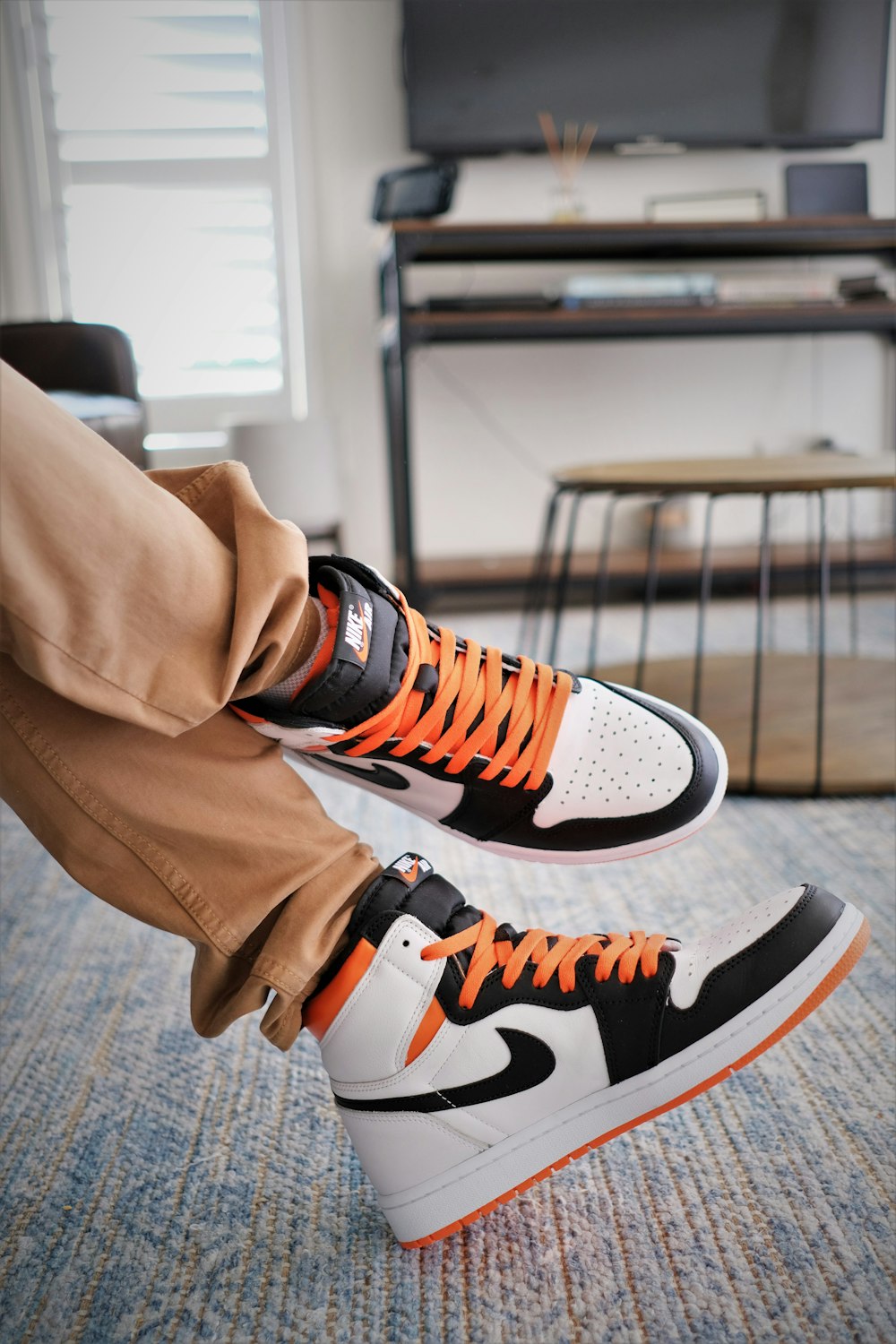 a person wearing orange and black sneakers in a living room