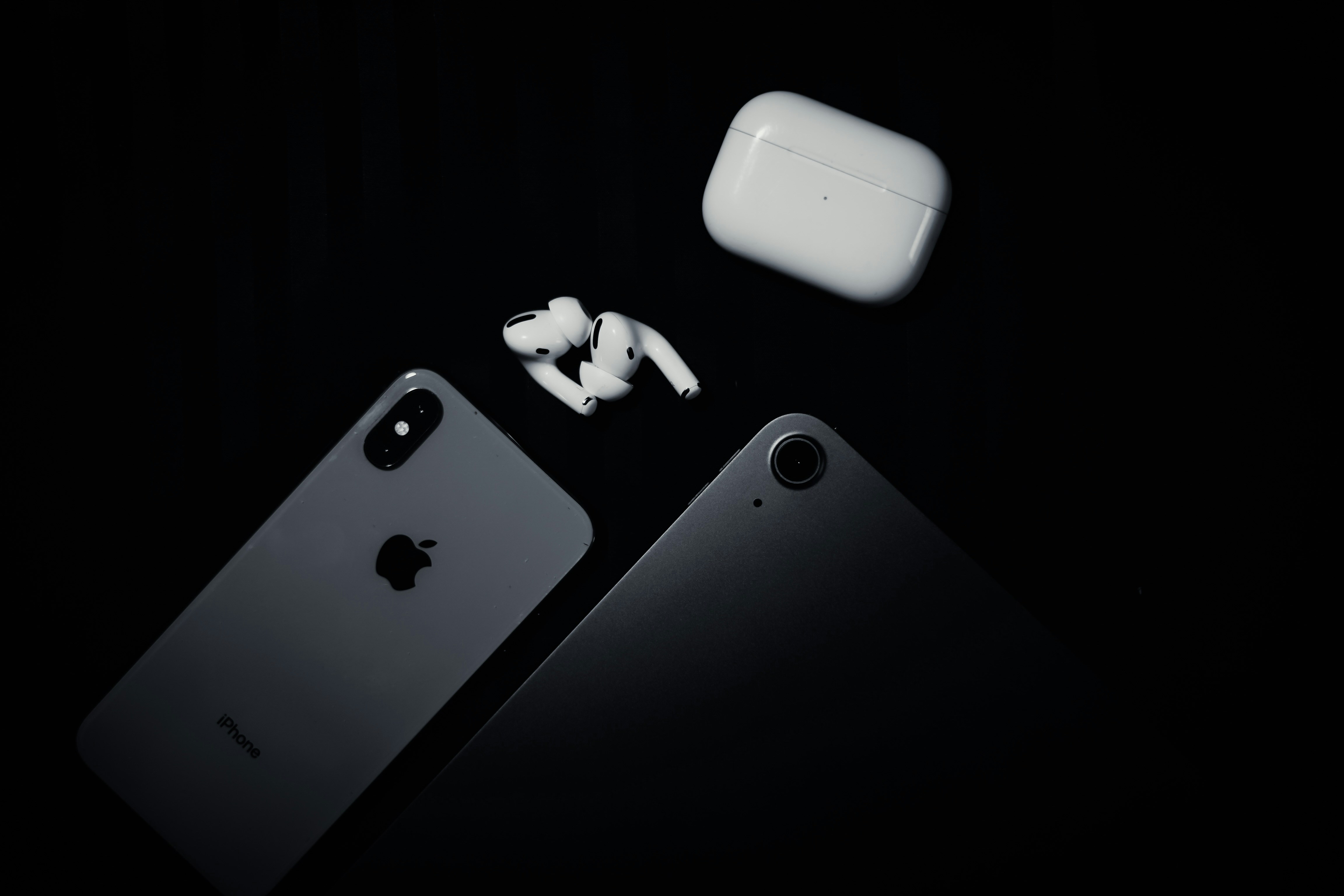 an iphone, ear buds, and an airpods sitting next to each other