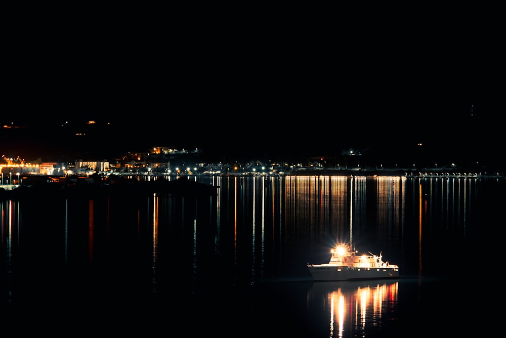 a boat floating on top of a lake at night