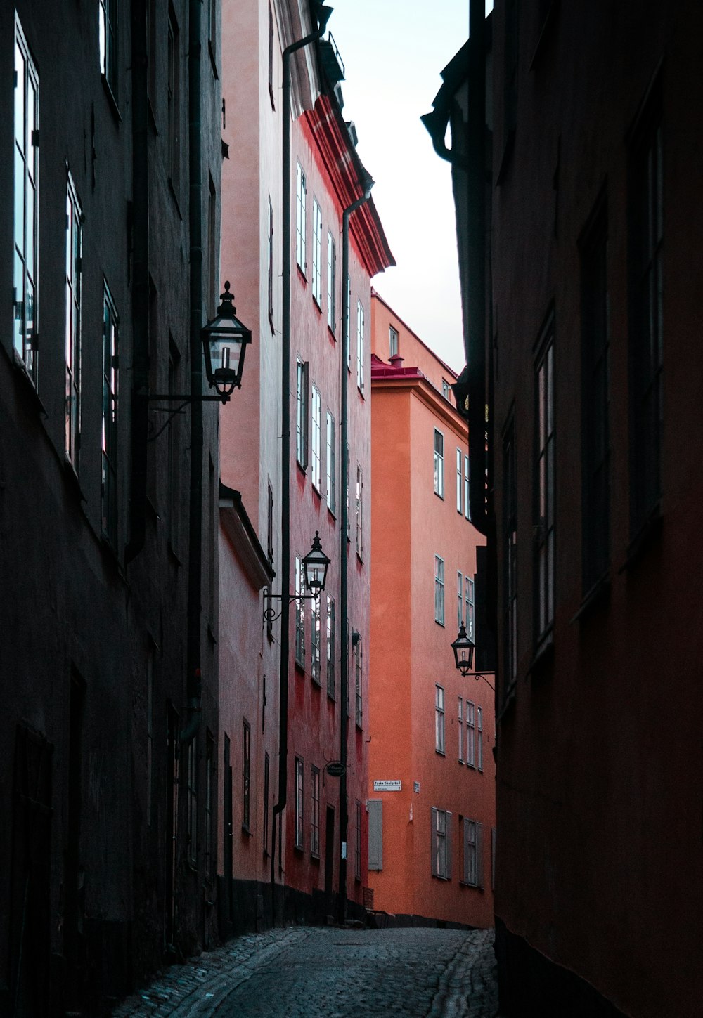 a narrow city street with red buildings on both sides